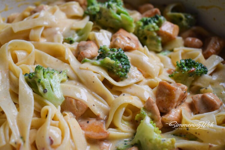 Close-up of creamy butter garlic chicken and broccoli fettuccine in the pan showing sauce texture