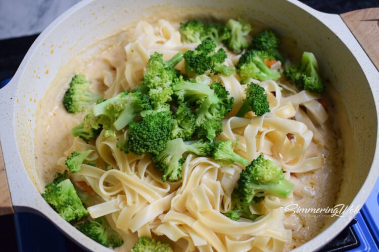 Fettuccine and broccoli tossed into the creamy sauce with chicken in the pan