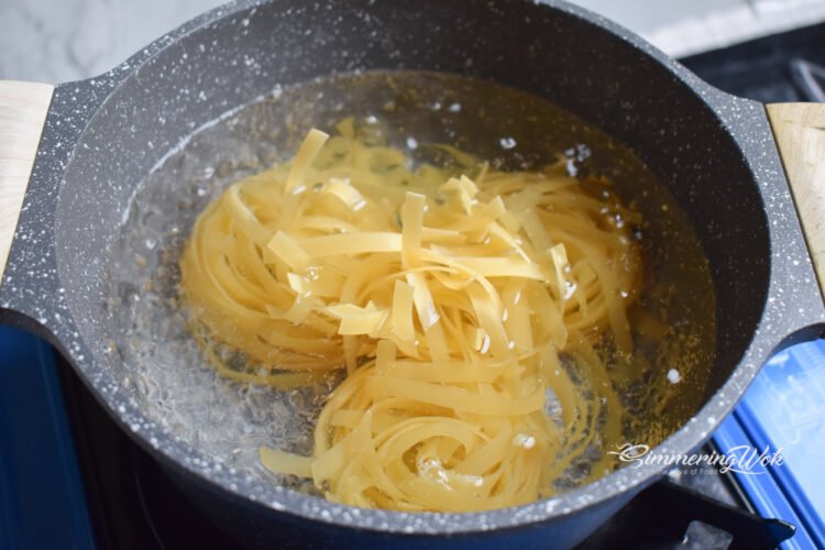 Fettuccine pasta boiling in a large pot of salted water with visible bubbles