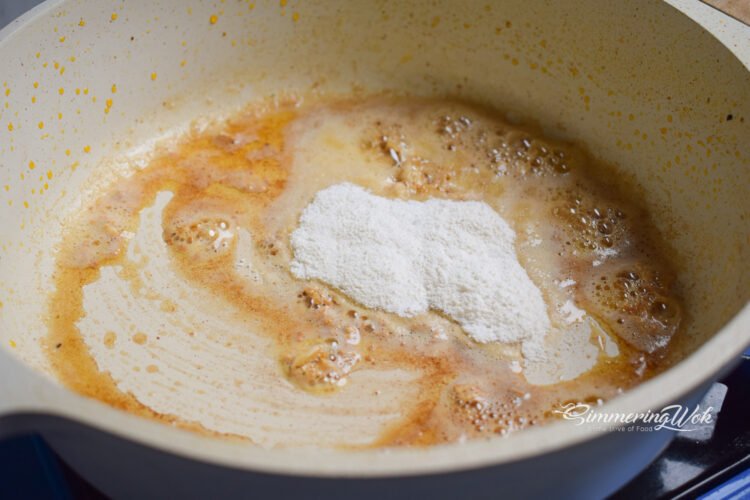 Flour added to the butter and garlic mixture forming a light roux in the pan