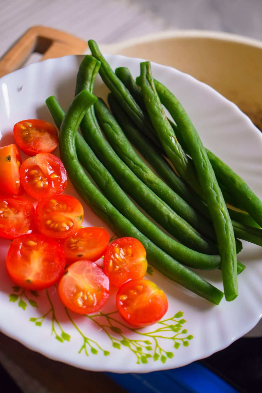 Fresh French green beans and halved cherry tomatoes on a plate