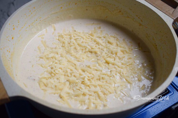 Parmesan cheese being stirred into the creamy garlic sauce melting beautifully