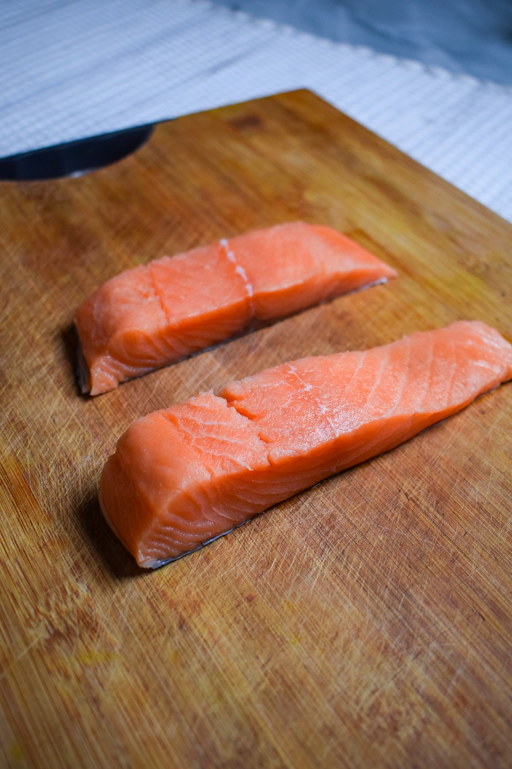 Fresh raw salmon fillets on a wooden cutting board ready for seasoning