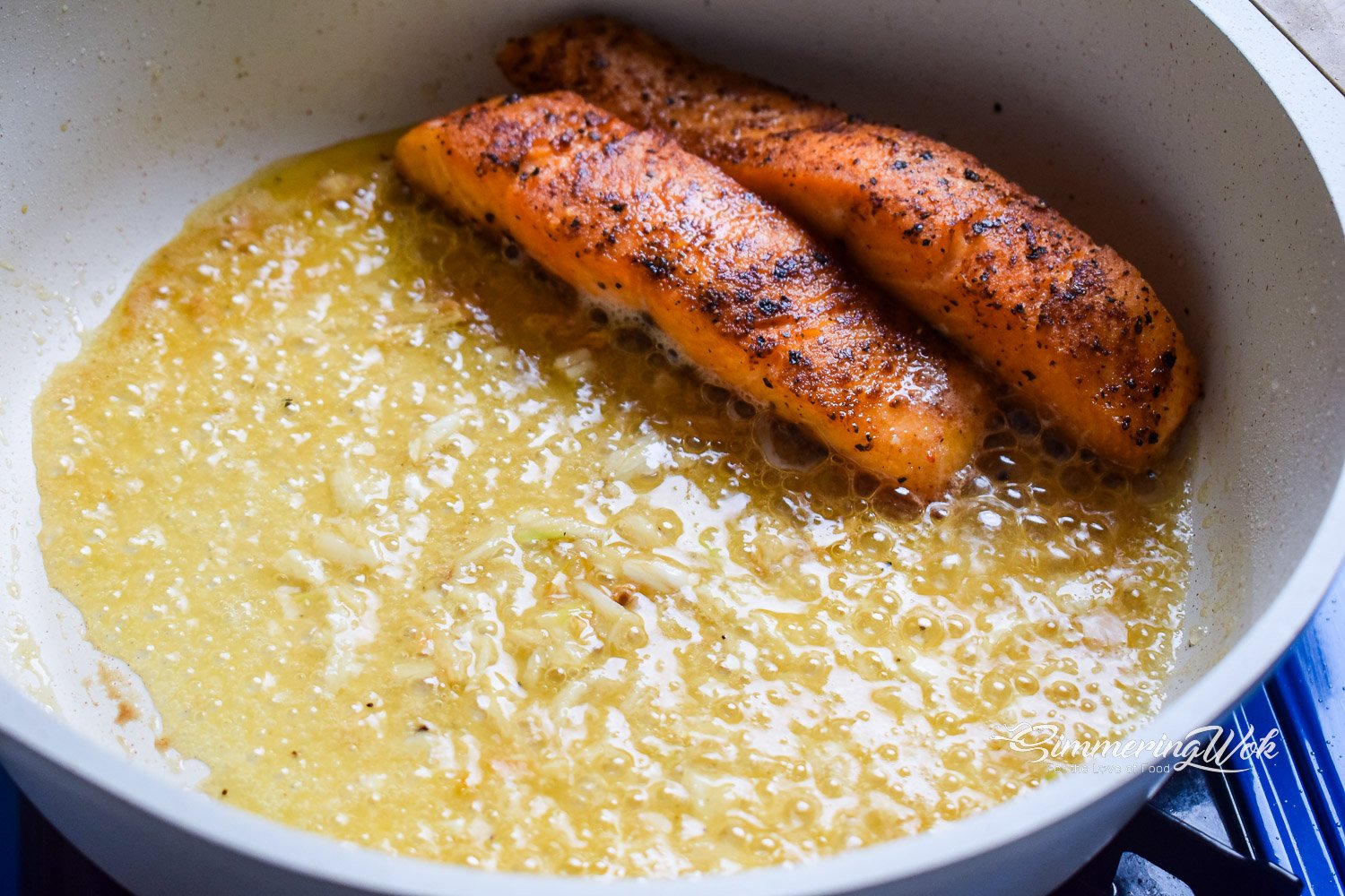 Salmon fillets being basted in garlic butter sauce