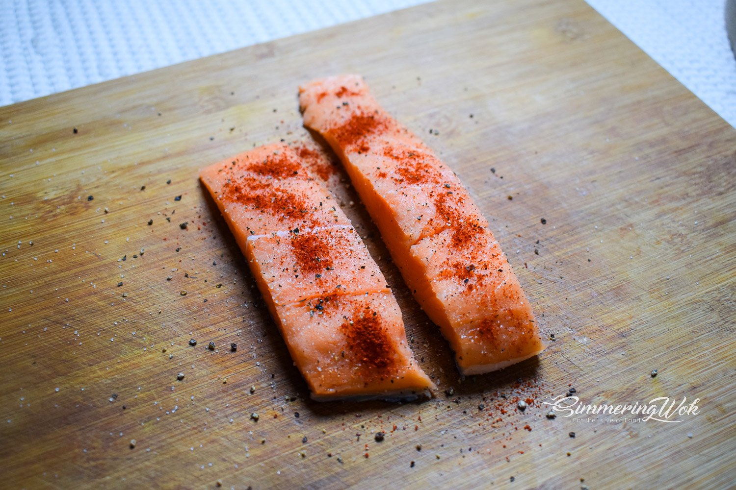 Salmon fillets seasoned with salt pepper and paprika on a cutting board